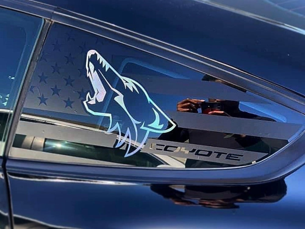 Blue Ford Mustang with custom quarter window decal featuring a stylized coyote logo and American flag pattern, showcasing the S550 model's sleek design and personalized aesthetic.