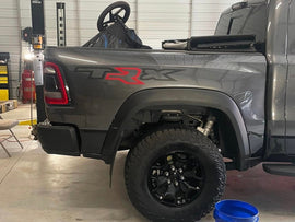Gray RAM TRX truck bed with custom TRX logo decal featuring black letters and red R, showcasing the product on a vehicle in a garage setting