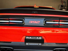 Load image into Gallery viewer, Close-up rear view of a red Dodge Challenger, showcasing the taillight area with a black divider strip featuring a red 392 logo, highlighting the customizable taillight divider decal product for 2015+ models.