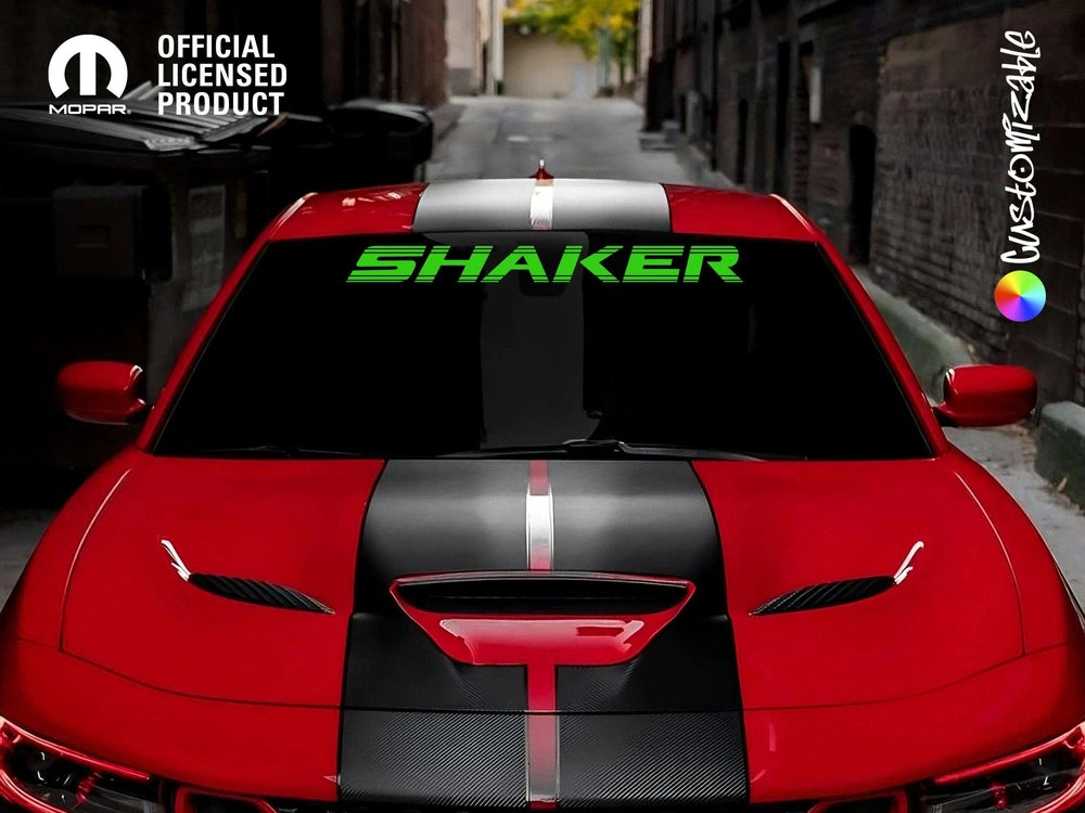 Red Dodge Challenger with black racing stripes and green 'SHAKER' windshield decal, parked on urban street. Official licensed product logo in top left corner.