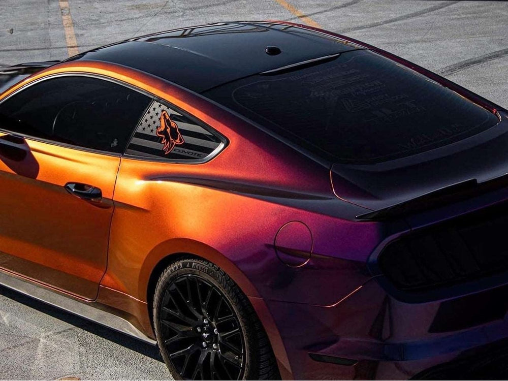Ford Mustang S550 with custom quarter window decals featuring American flag design and Coyote logo, showcased in vibrant orange and purple color-shifting paint on a concrete surface