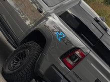 Load image into Gallery viewer, RAM TRX truck bedside decal featuring TRX logo with customized blue R, displayed on silver vehicle body above off-road tire and near taillight, showcasing product application and design