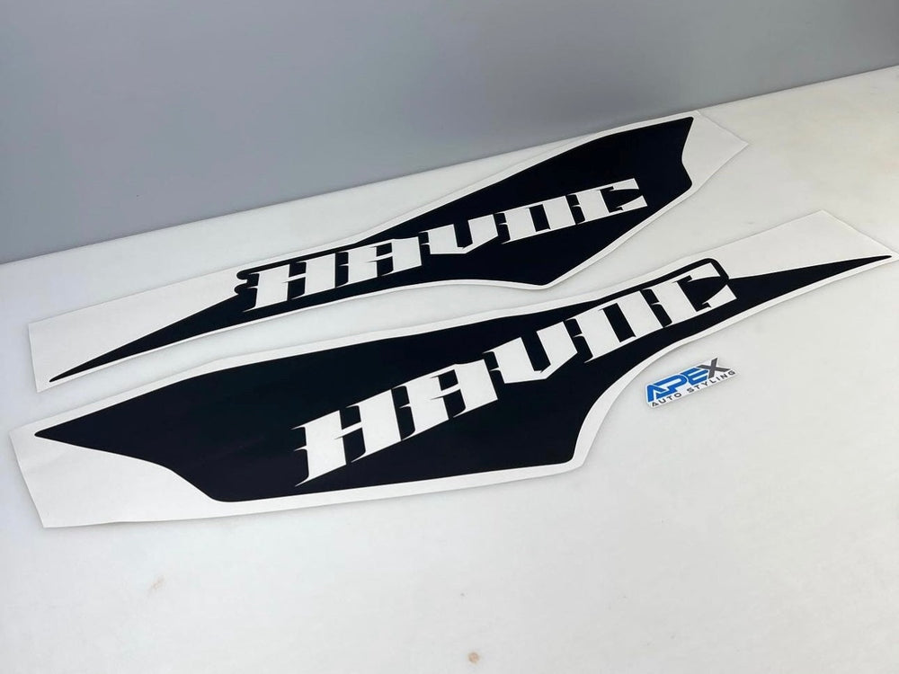Two black and white RAM TRX Havoc Edition bedside decals with angular design, displaying HAVOC text, alongside a small blue squeegee tool for installation