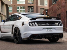 Load image into Gallery viewer, White Ford Mustang S550 parked on street, rear view showcasing sleek design, black wheels, and distinctive taillights. Urban brick buildings in background.