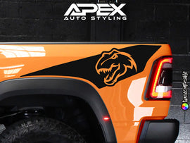 Orange RAM TRX truck with custom black bedside decal featuring T-Rex dinosaur logo, showcasing Apex Auto Styling products for vehicle customization and personalization