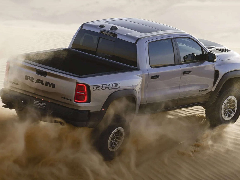 RAM RHO pickup truck driving through dusty terrain, showcasing bedside decals and rugged performance