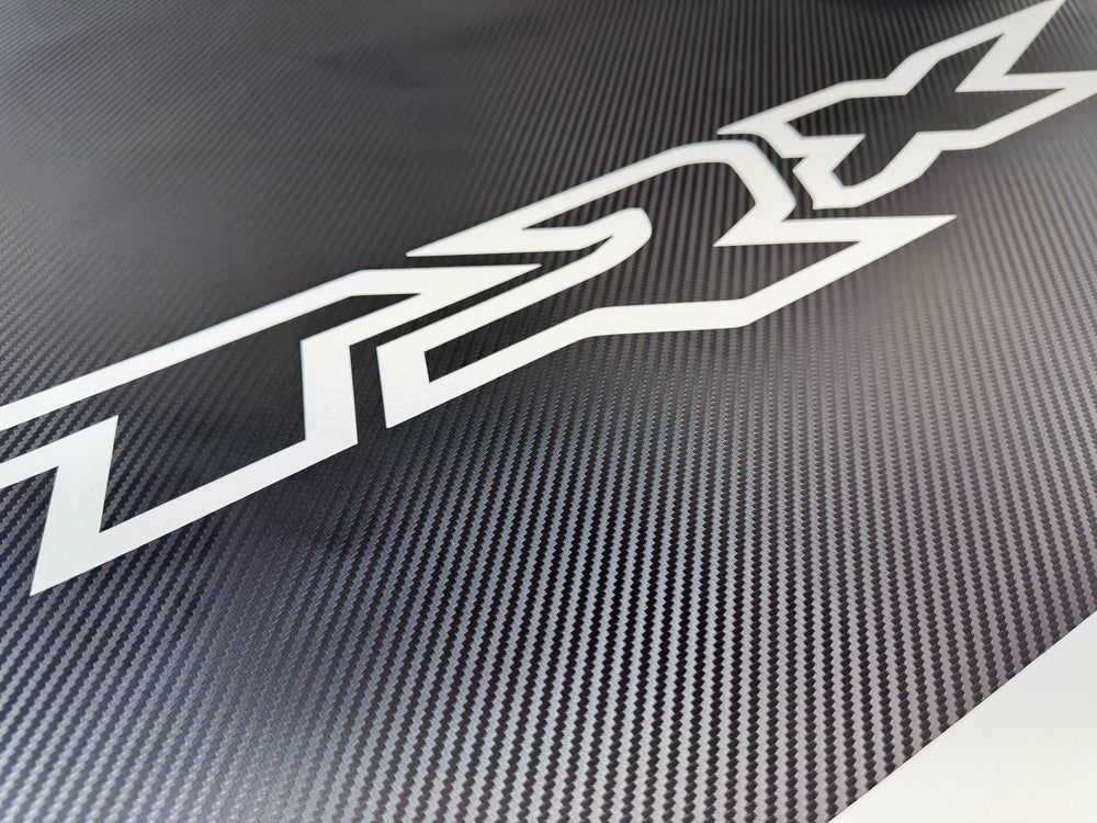 RAM TRX hood decal with white logo cutout on carbon fiber textured background, showcasing OEM-style design for truck customization