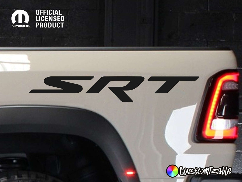 Close-up of RAM TRX truck bedside featuring large black SRT logo decal, with part of red taillight visible. Official licensed product logo in top left corner. White truck body with glossy finish.