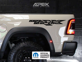 RAM TRX bedside decal featuring OEM logo and US flag design on a white truck, showcasing the product's appearance and placement on the vehicle's side panel near the rear wheel arch