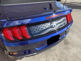 Blue Ford Mustang rear view with American flag-inspired decklid decal featuring stars and stripes design, showcasing custom styling on the trunk lid between distinctive taillights