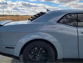 Silver Dodge Challenger with honeycomb pattern quarter window decal, parked on open road under cloudy sky, showcasing sleek design and custom appearance