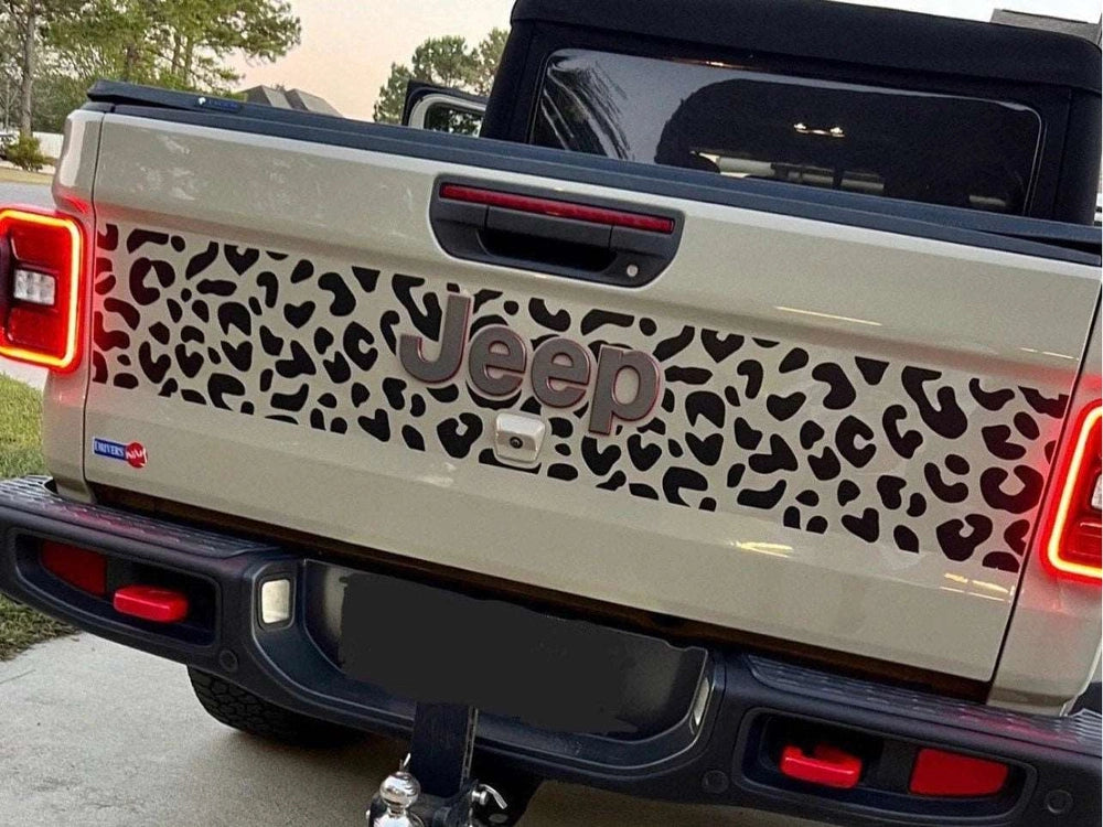 Jeep Gladiator tailgate with custom cheetah print decal, showcasing unique design and Jeep logo, parked in driveway with tail lights visible