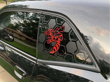 Load image into Gallery viewer, Dodge Challenger quarter window with custom red angry hornet logo decal on black hexagonal background, showcasing unique vinyl design for car customization