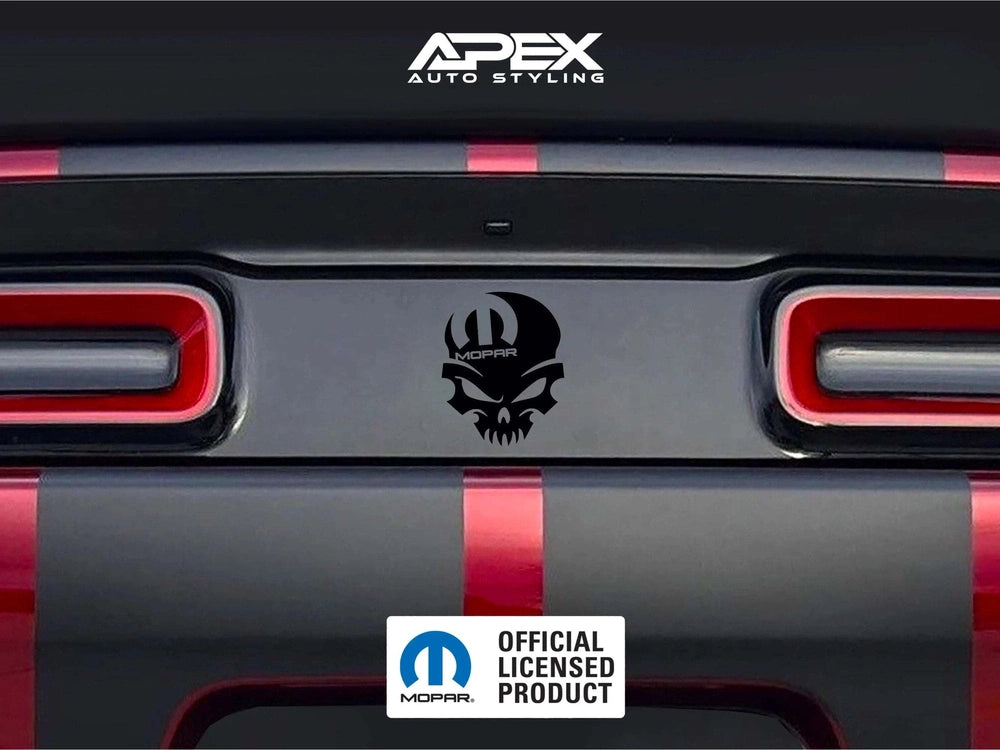 Dodge Challenger taillight divider with black MOPAR skull logo decal, showcasing customizable design options for car enthusiasts. Red taillights and rear bumper visible.