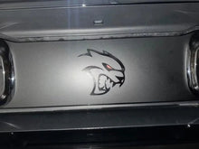 Load image into Gallery viewer, Dodge Challenger taillight divider with Hellcat Redeye logo decal applied, featuring a stylized cat head with glowing red eye between taillights on silver-gray surface