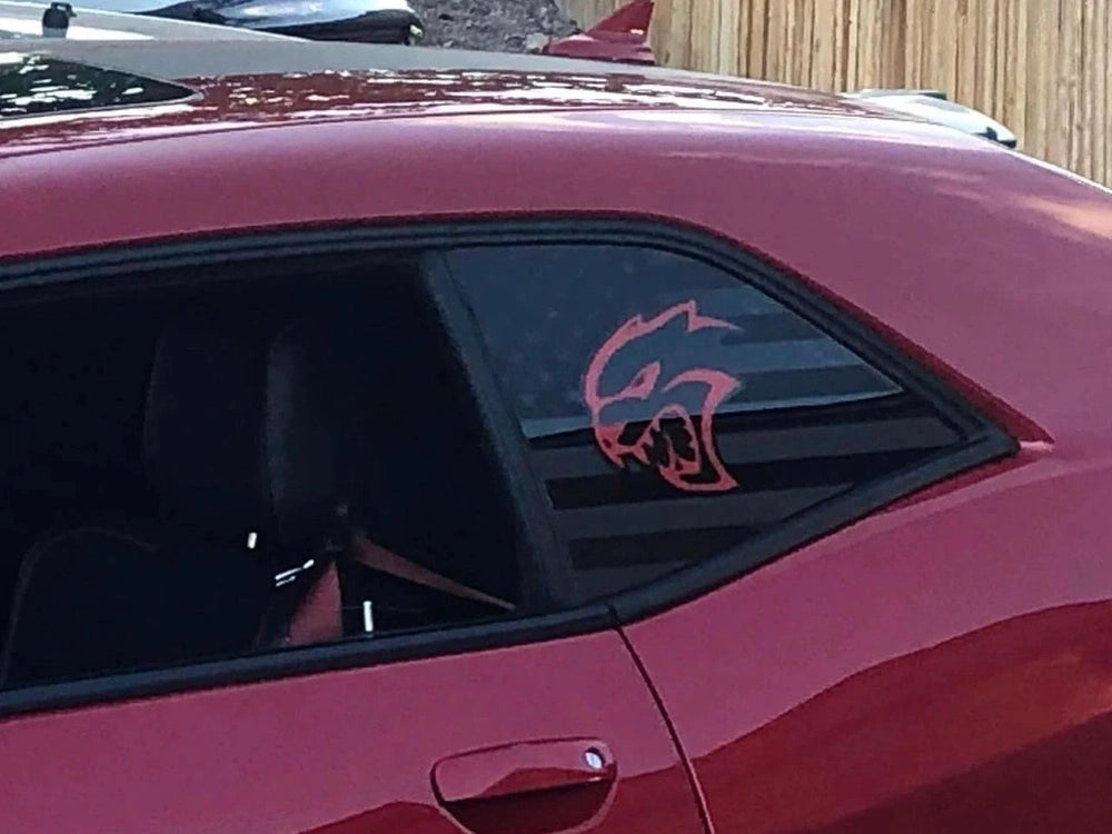 Challenger quarter window with custom Hellcat logo decal in pink on dark tinted glass, contrasting against maroon exterior, showcasing sleek muscle car styling