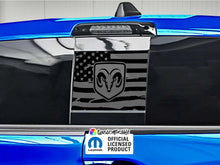 Load image into Gallery viewer, RAM truck rear sliding window with black American flag decal featuring RAM logo, displayed on blue vehicle exterior. Official licensed product label visible.