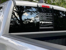 Load image into Gallery viewer, RAM truck rear sliding window with custom black flag decal featuring Rebel logo, showcasing the product on a silver vehicle parked outdoors with trees reflected in the window