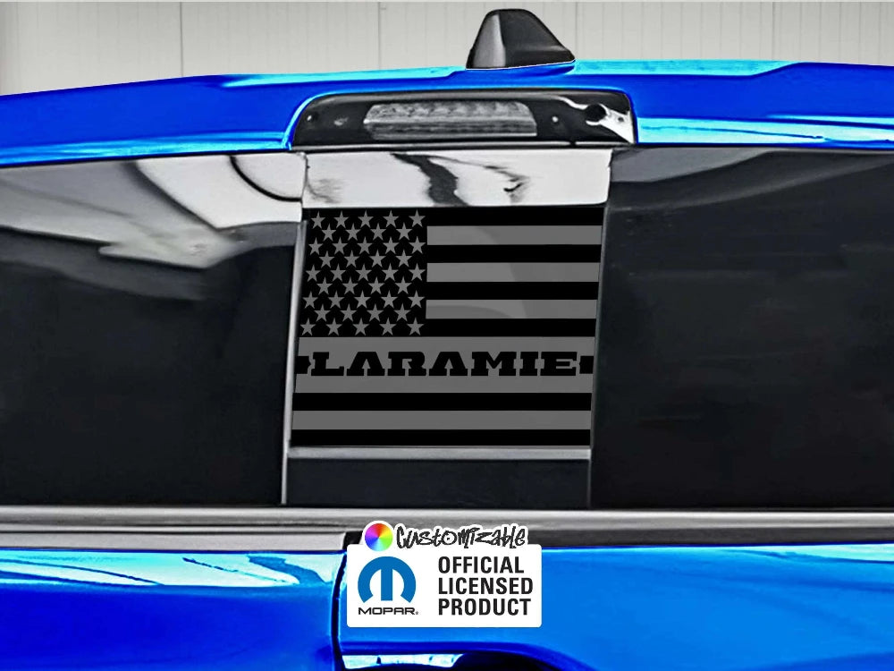 RAM truck rear sliding window with black American flag decal featuring Laramie logo, blue exterior, official licensed product sticker visible