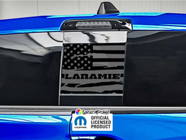 RAM truck rear sliding window with black American flag decal featuring Laramie logo, showcased on blue vehicle exterior with official licensed product label