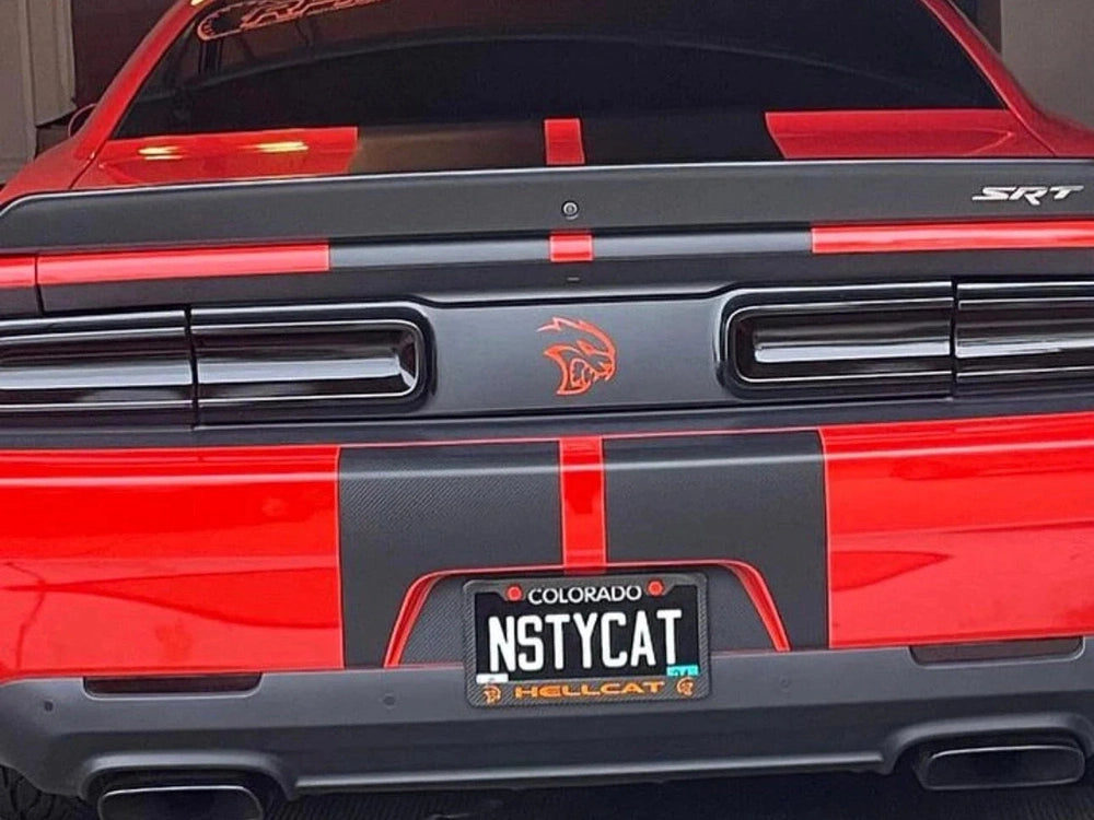 Red Dodge Challenger rear view showing custom taillight divider decal with Hellcat logo and SRT badge, featuring black racing stripes and a personalized license plate reading "N5TYCAT