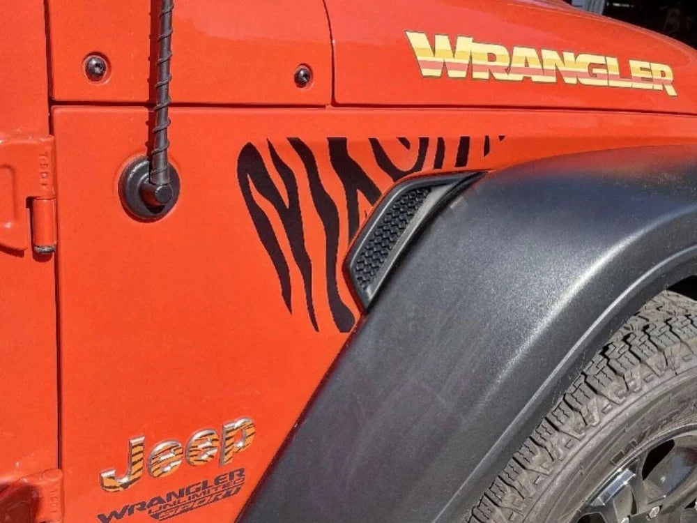 Orange Jeep Wrangler fender with zebra stripe decal, showcasing custom fender vent design for Wrangler and Gladiator models. Close-up view highlighting the contrast between vibrant vehicle color and black striped pattern.