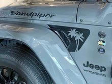 Load image into Gallery viewer, Close-up of a silver Jeep Wrangler fender with &quot;Sandpiper&quot; text and palm tree decal on the vent, showcasing custom fender vent decals for Jeep Wrangler and Gladiator models