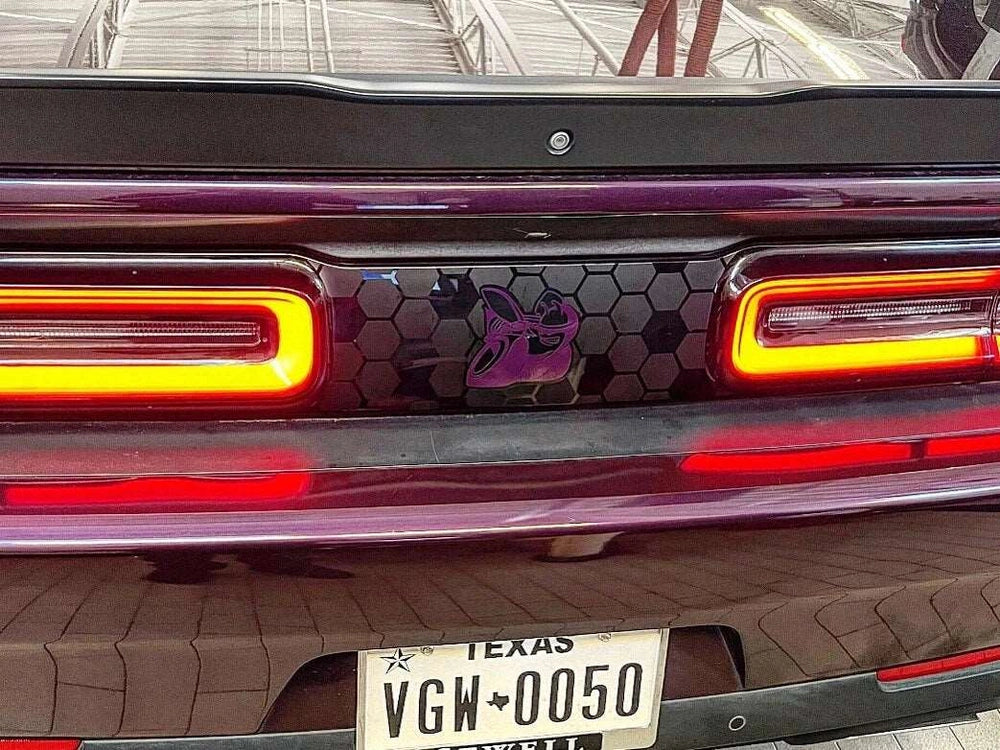 Dodge Challenger rear view with custom taillight divider decal featuring purple Scat Pack logo on honeycomb pattern, illuminated taillights, and Texas license plate visible