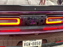 Load image into Gallery viewer, Dodge Challenger rear view with custom taillight divider decal featuring purple Scat Pack logo on honeycomb pattern, illuminated taillights, and Texas license plate visible