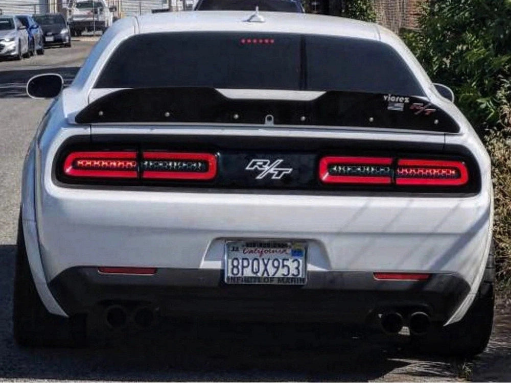 White Dodge Challenger rear view showcasing custom taillight divider decal with R/T logo, enhancing the vehicle's sleek and sporty appearance. Distinctive red LED taillights flank the black divider, creating a bold contrast against the car's white body.