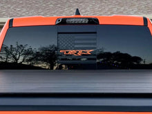 Load image into Gallery viewer, Rear window of orange RAM truck with black TRX logo decal and American flag design, showcasing custom sliding window decals for 2009+ RAM pickups