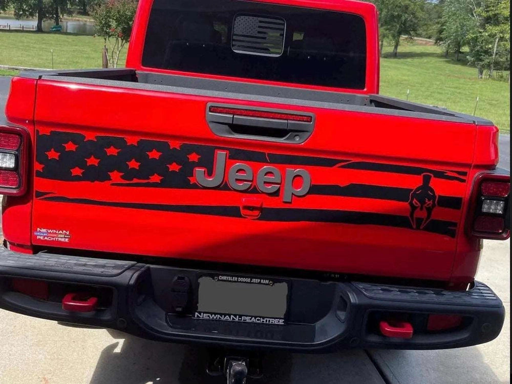 Red Jeep Gladiator tailgate with black American flag design, Jeep logo, and Gladiator emblem decal. Custom patriotic vinyl graphic enhancing the vehicle's appearance, showcasing brand pride and rugged style.