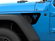 Load image into Gallery viewer, Close-up of a bright blue Jeep Wrangler or Gladiator fender, featuring a black biohazard logo decal on the vent, showcasing the custom vinyl accessory for Jeep vehicles