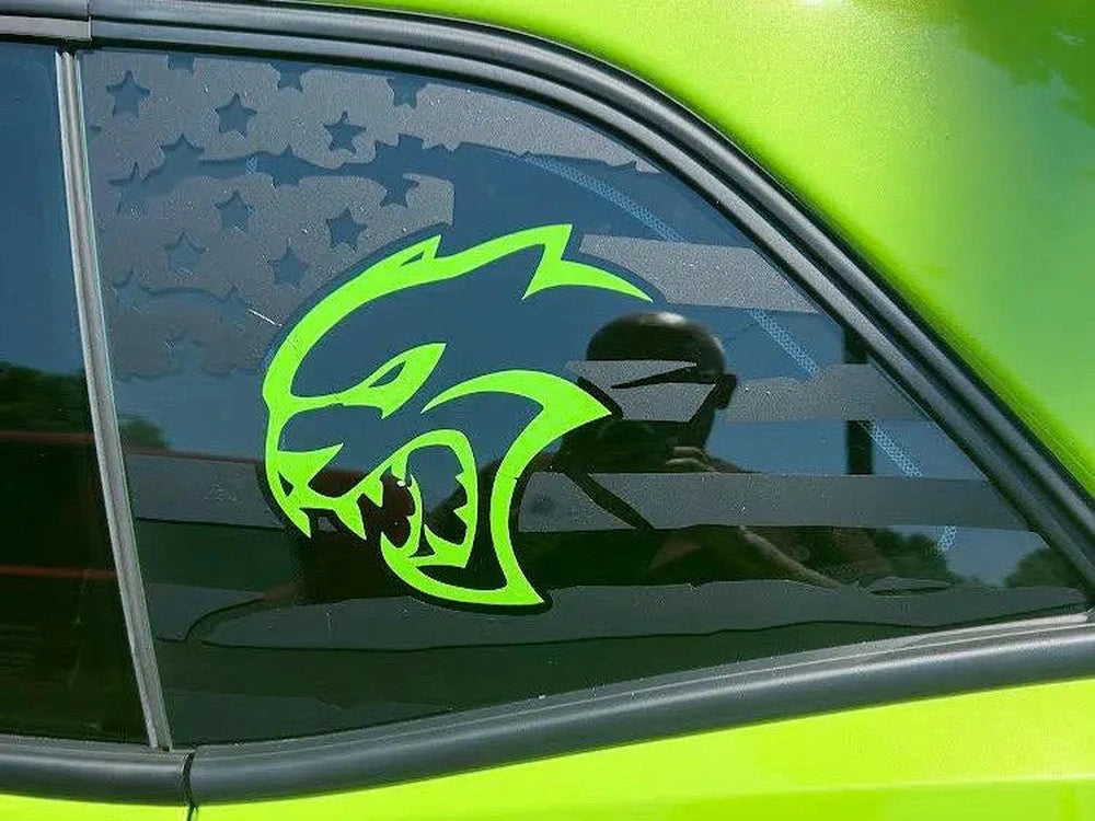 Neon green Hellcat logo decal on quarter window of bright green Dodge Challenger, showcasing custom vinyl application and vibrant color contrast against star-patterned window tint