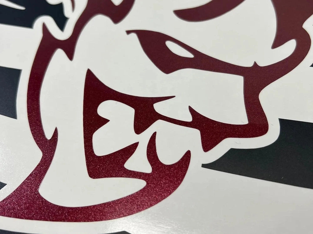 Close-up of maroon Demon logo decal on white surface, showing intricate details of fierce, stylized face design for Dodge Challenger quarter window customization