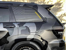 Load image into Gallery viewer, Jeep Grand Cherokee with American flag decal on quarter window, showcasing custom patriotic design for 2011-2021 models. Gray vehicle exterior with black trim, highlighting the matte black vinyl application on rear side window.