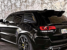 Load image into Gallery viewer, Black Jeep Grand Cherokee with American flag quarter window decals, showcasing patriotic custom design on a sleek SUV against textured background