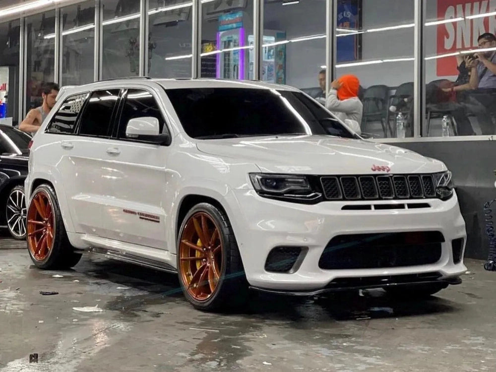 White Jeep Grand Cherokee SRT with custom copper-colored wheels parked in front of a store, showcasing the sleek design and performance-oriented styling of the high-performance SUV model.
