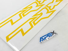 Load image into Gallery viewer, Yellow TRX logo windshield banner decal with geometric design on white background, next to blue and gray APEX Auto Styling logo, showcasing custom vehicle graphics for truck rear windows